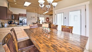 Une cuisine spacieuse avec des meubles de rangement en bois, une grande table à manger en bois et un lustre.
