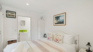 A bedroom with a bed, a nightstand, a bedside table, a mirror, a wardrobe, a dresser, and a framed picture on the wall.