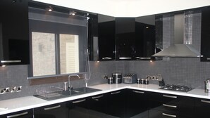 A modern kitchen with black cabinets, a white countertop, and a stainless steel range hood. - Luxury 5 star villa private pool and patio in quiet village, Larnaca. (Oroklini)