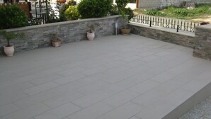 A spacious outdoor patio area with tiled flooring, surrounded by stone walls and potted plants. - Luxury 5 star villa private pool and patio in quiet village, Larnaca. (Oroklini)