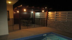 A swimming pool with a glass enclosure and a patio area with outdoor furniture. - Luxury 5 star villa private pool and patio in quiet village, Larnaca. (Oroklini)