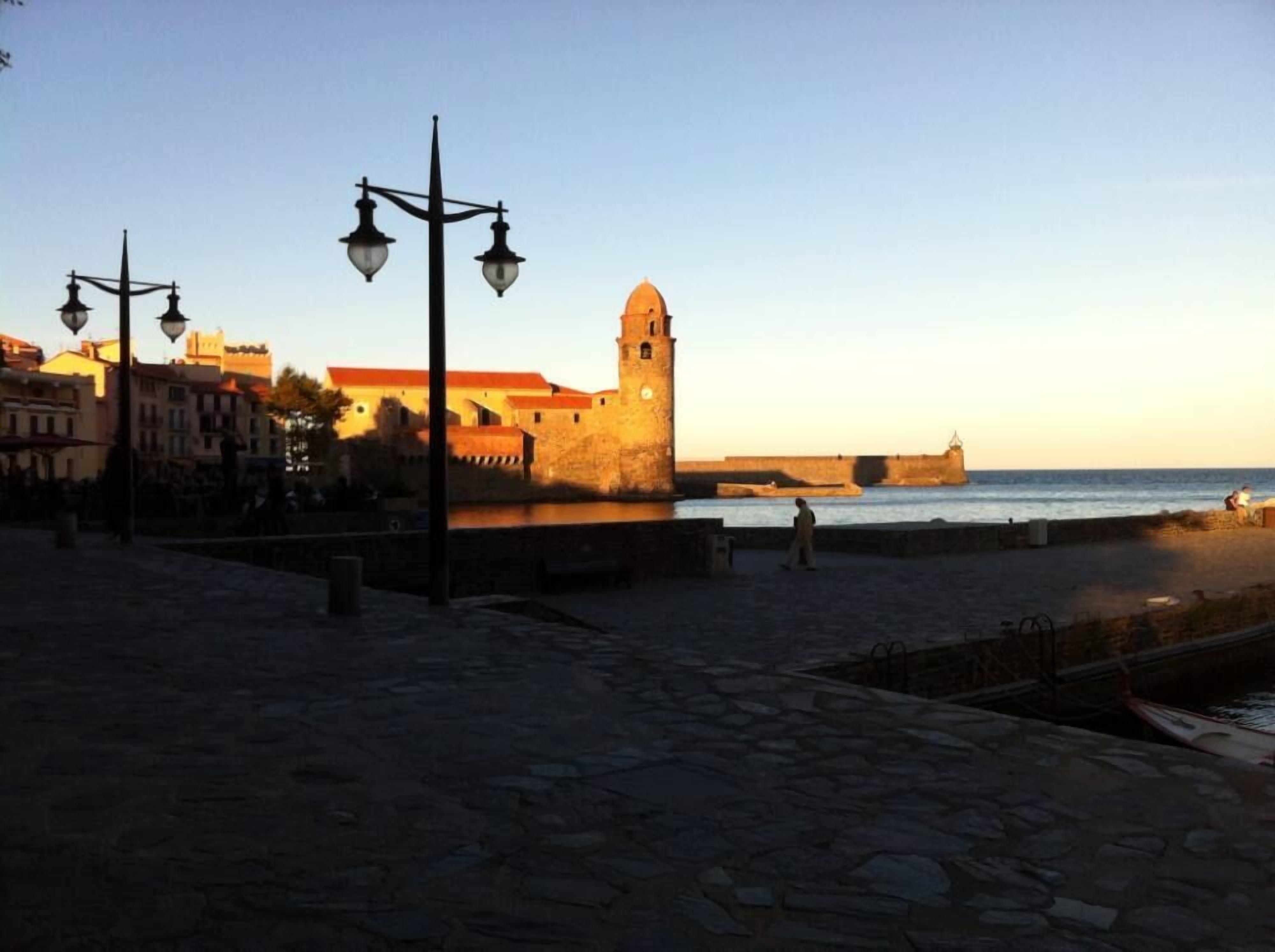Un paseo marítimo adoquinado con una torre histórica y edificios en el fondo.