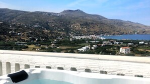 A hot tub with a view of a coastal town and a mountain in the background.