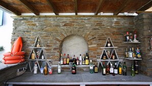 A stone fireplace with a wooden ceiling, surrounded by shelves with various bottles.