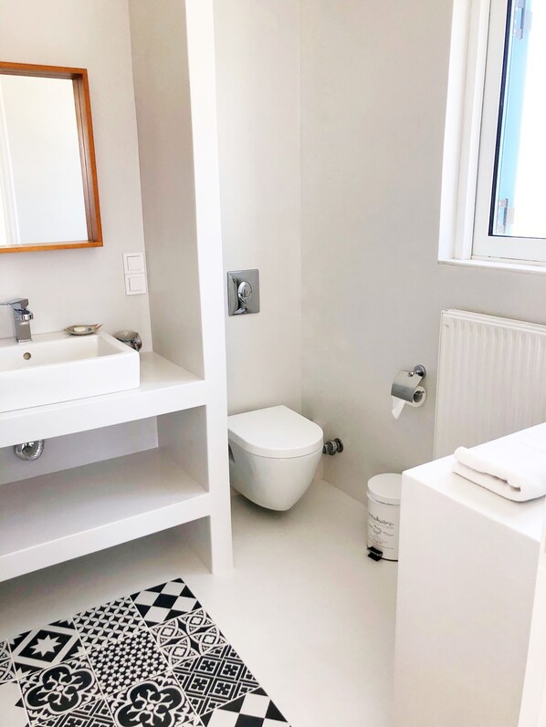 Un baño moderno con lavamanos, inodoro y ventana.