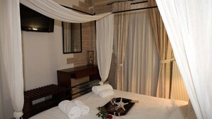 A neatly made bed with white linens, a bedside table with a bottle and a glass, and a starfish decoration.