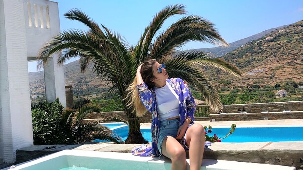 A person sitting by a pool with a mountainous backdrop.
