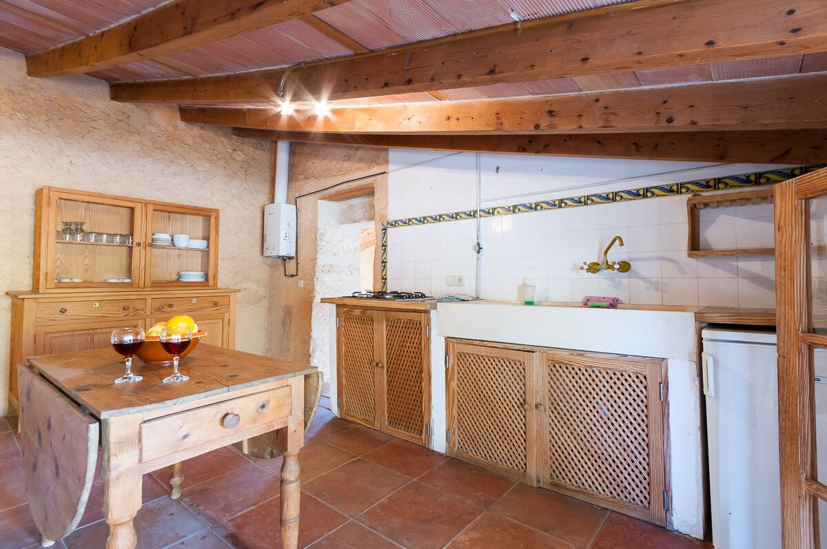 Une cuisine rustique avec des meubles en bois, un pare-feu en carreaux et une petite table sur laquelle on trouve des verres et des citrons.