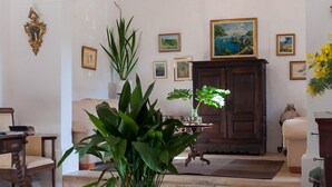 Un salón amplio con una planta en maceta grande, un mueble de madera y un cuadro en la pared.