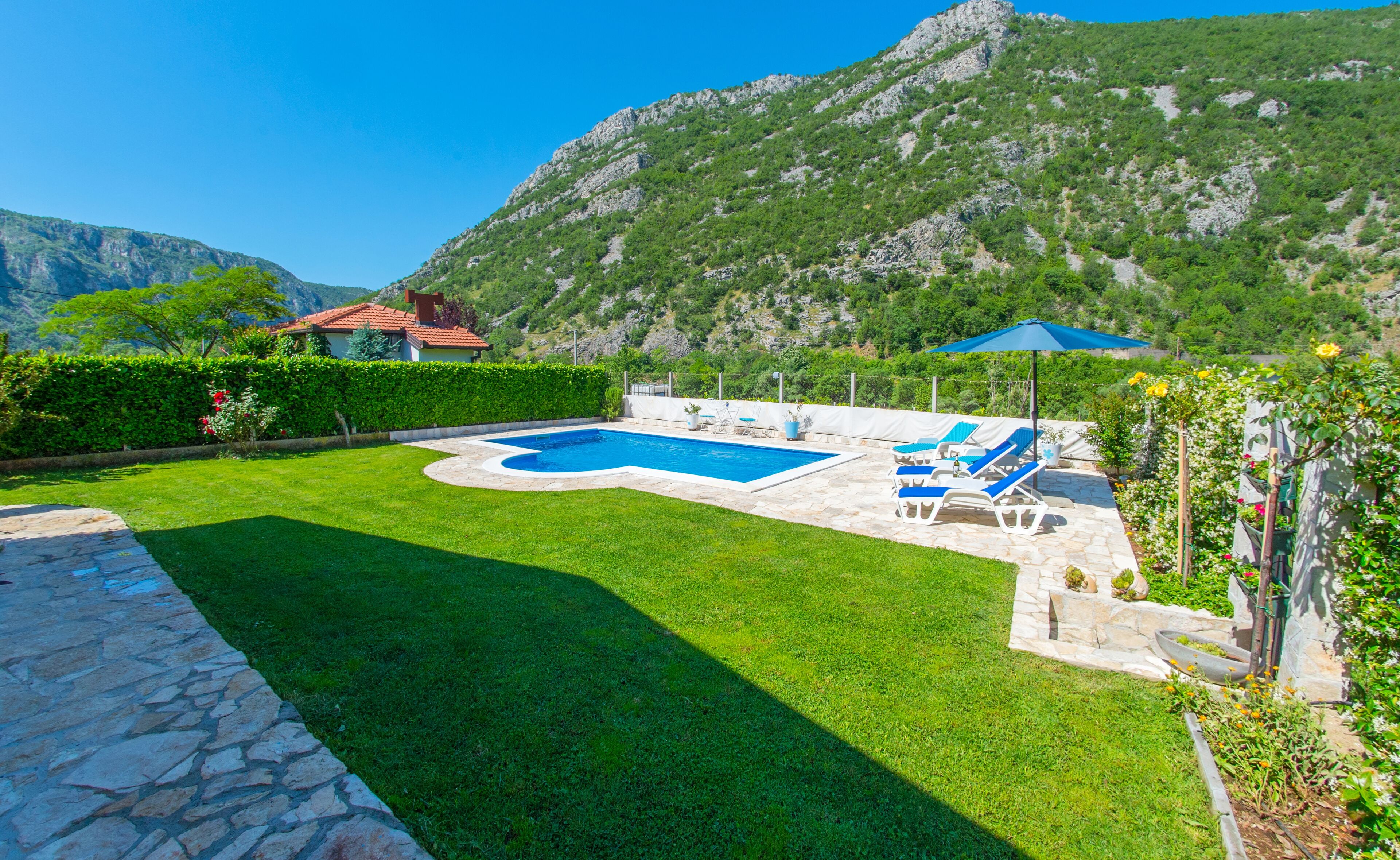 A swimming pool with lounge chairs and a mountain backdrop.