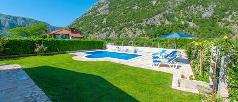 A swimming pool with lounge chairs and a mountain backdrop.