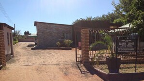A dirt road leading to a lodge with a signboard. - Eland Lodge (Livingstone)