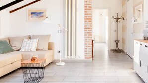 A modern living room with a sofa, a coffee table, and a lamp. There is a brick column and a radiator on the wall. - Lamansarda, romantic place for your holidays. (La Spezia)