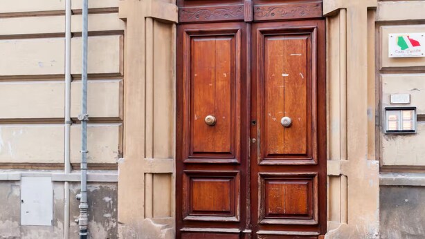 A double wooden door with intricate carvings, set in a beige building facade. - Lamansarda, romantic place for your holidays. (La Spezia)