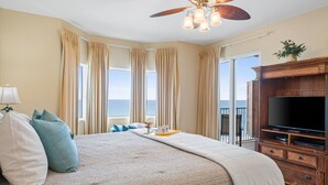 Una habitación de hotel con una cama grande, televisión y balcón con vistas al océano.