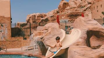 Slide into relaxation at this resort's natural rock formation-inspired water slide, surrounded by a clear pool and soothing water feature.