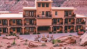 A multi-story hotel with balconies, a courtyard with outdoor seating, and a view of red rock formations.