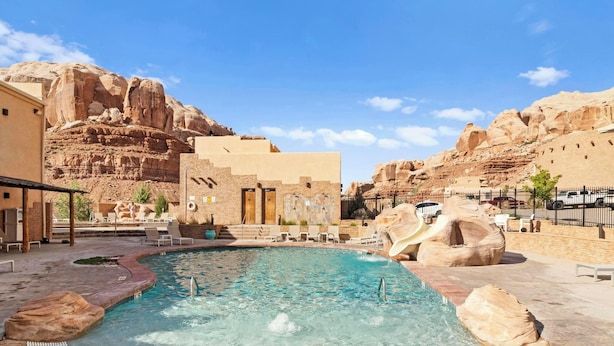 A pool area with a hot tub, lounge chairs, and a rock slide.