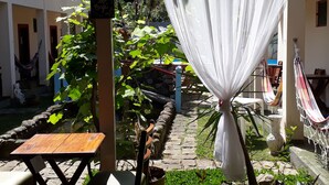 A courtyard with a hammock, a table, and a chair. - Pousada Bela Paraty (Paraty)