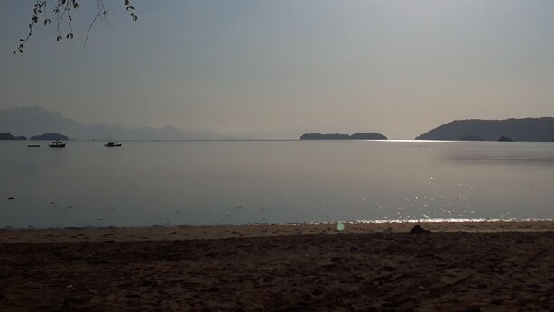 A calm lake with boats, distant mountains, and a sandy beach. - Pousada Bela Paraty (Paraty)