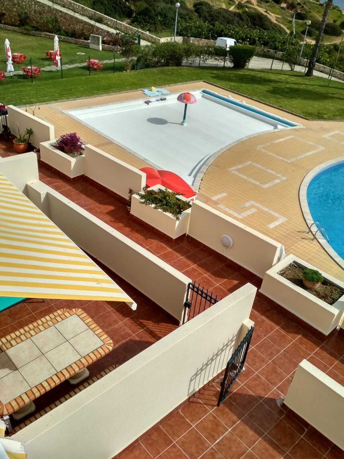 Un área de piscina en la azotea con una sombrilla, asientos al aire libre y vistas del paisaje circundante.