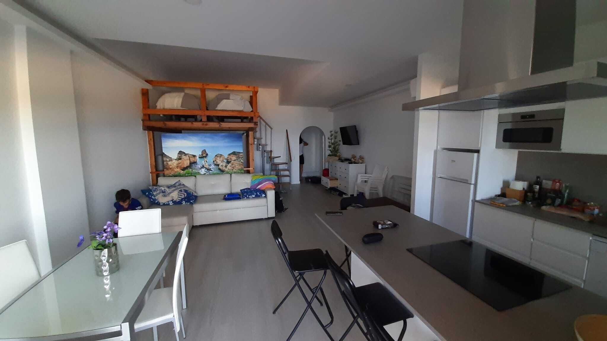 Une cuisine moderne avec un coin repas, un canapé et un téléviseur fixé au mur.