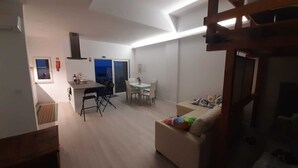 Ein modernes Wohnzimmer mit Sofa, Esstisch und Küchenzeile mit Herd und Spüle.
