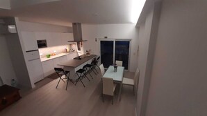 Eine moderne Küche mit weißen Schränken, einer zentralen Kochinsel und einem Essbereich mit Tisch und Stühlen.