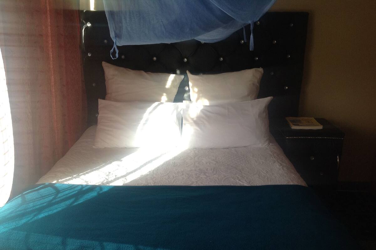 Ein Bett mit weißer Bettwäsche, einem blauen Überwurf und einem Baldachin.