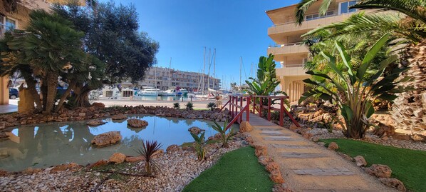 A marina with boats, a small pond with rocks, and a pathway leading to a building.