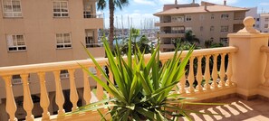 A balcony with a railing, overlooking a marina with boats and buildings in the background.