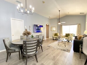 Relax in this stylish living area with a dining table, comfortable sofas, and a large flat-screen TV.