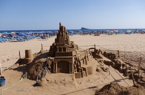 Un grand château de sable sur une plage, sous un ciel dégagé.