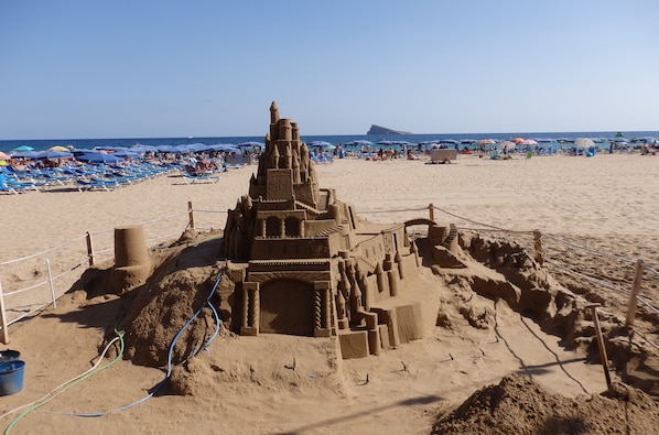 Ett stort sandslott på en strand under en klar himmel.