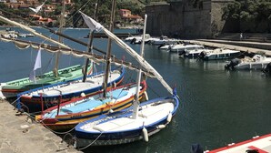 A harbor with boats docked, a castle in the background, and a clear sky. - House in beautiful Collioure with pool and sea views from both balconies (Collioure)