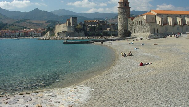 A coastal town with a historic stone building, a beach, and mountains in the background. - House in beautiful Collioure with pool and sea views from both balconies (Collioure)