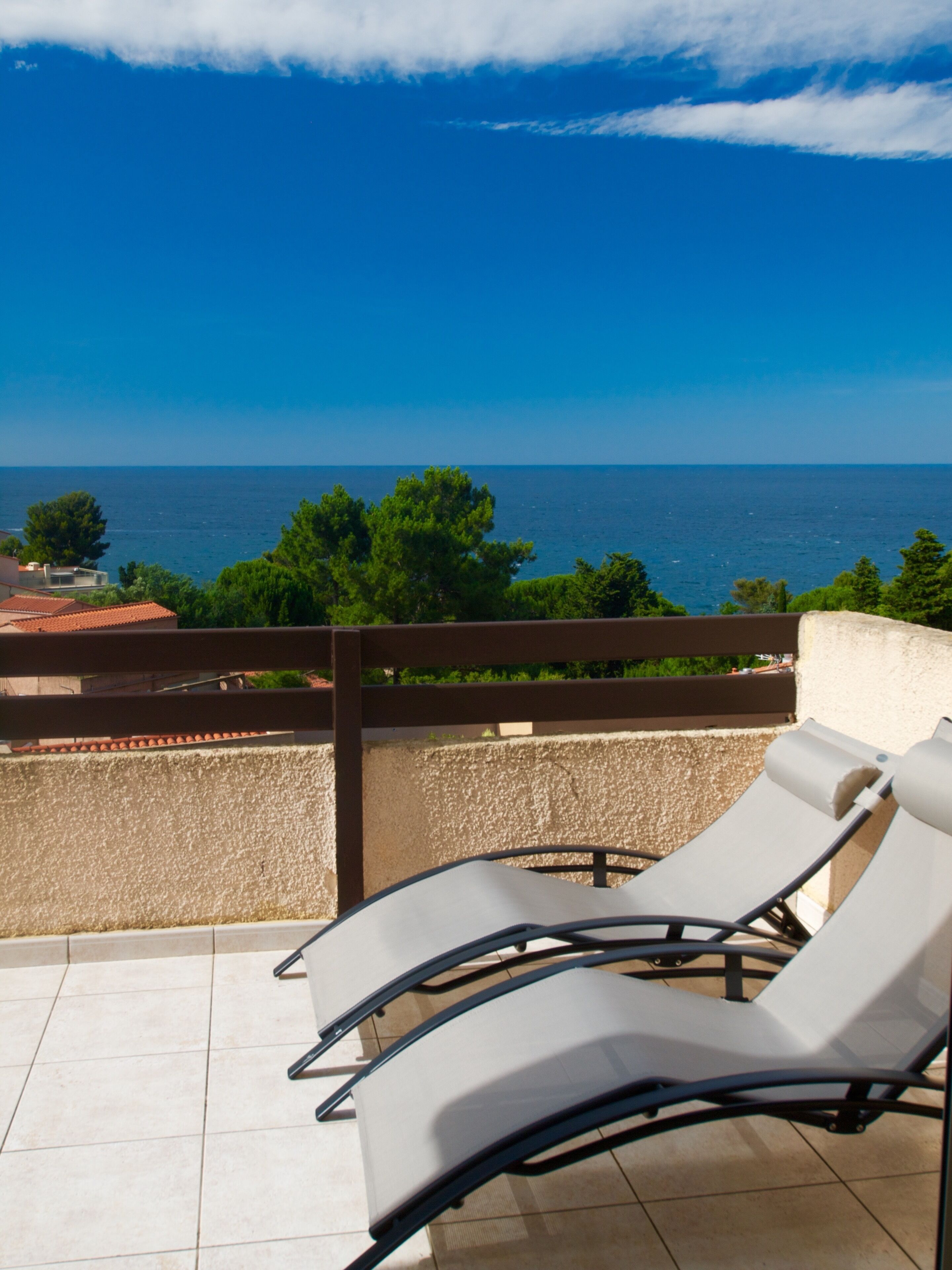 Un balcon avec deux fauteuils confortables donnant sur une vue imprenable sur la mer.
