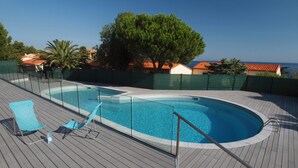 A swimming pool with a wooden deck, two blue lounge chairs, and a view of the sea. - House in beautiful Collioure with pool and sea views from both balconies (Collioure)