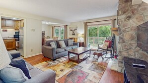 Ein Wohnzimmer mit grauem Sofa, einem Couchtisch und einem Kamin aus Stein.