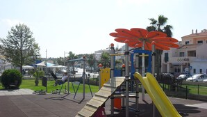 A playground with a yellow slide and a climbing structure.