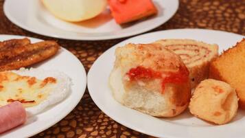A table with plates of food including bread rolls, a pastry, and a piece of meat.