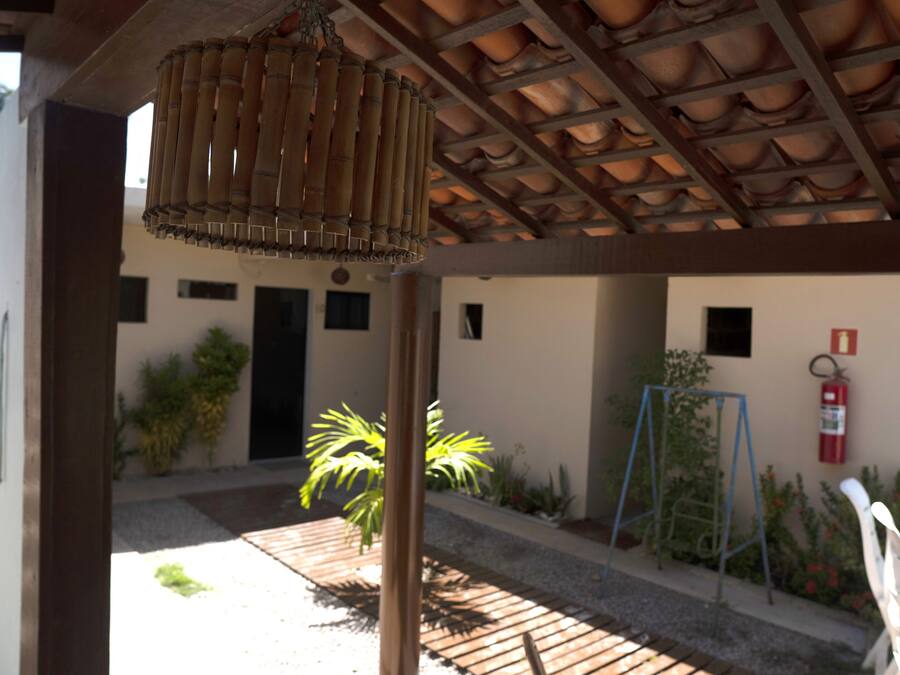 A covered outdoor area with a bamboo lamp, a fire extinguisher, and a small garden with plants and a swing set.