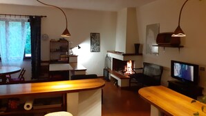 Ein gemütliches Wohnzimmer mit Kamin, Fernseher und Essbereich mit Tisch und Stühlen.