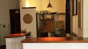 Eine Küche mit einer Holzausziehtischplatte, zwei roten Barhocker und einer hängenden Pendelleuchte.