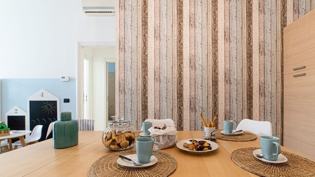 Un coin repas avec une table en bois mise pour deux personnes, comprenant une tasse bleue, une assiette de biscuits et un bocal en verre rempli de collations.