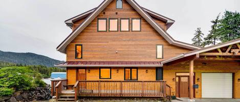 Eine große Holzhütte mit Satteldach, einer Veranda und einer Garage.