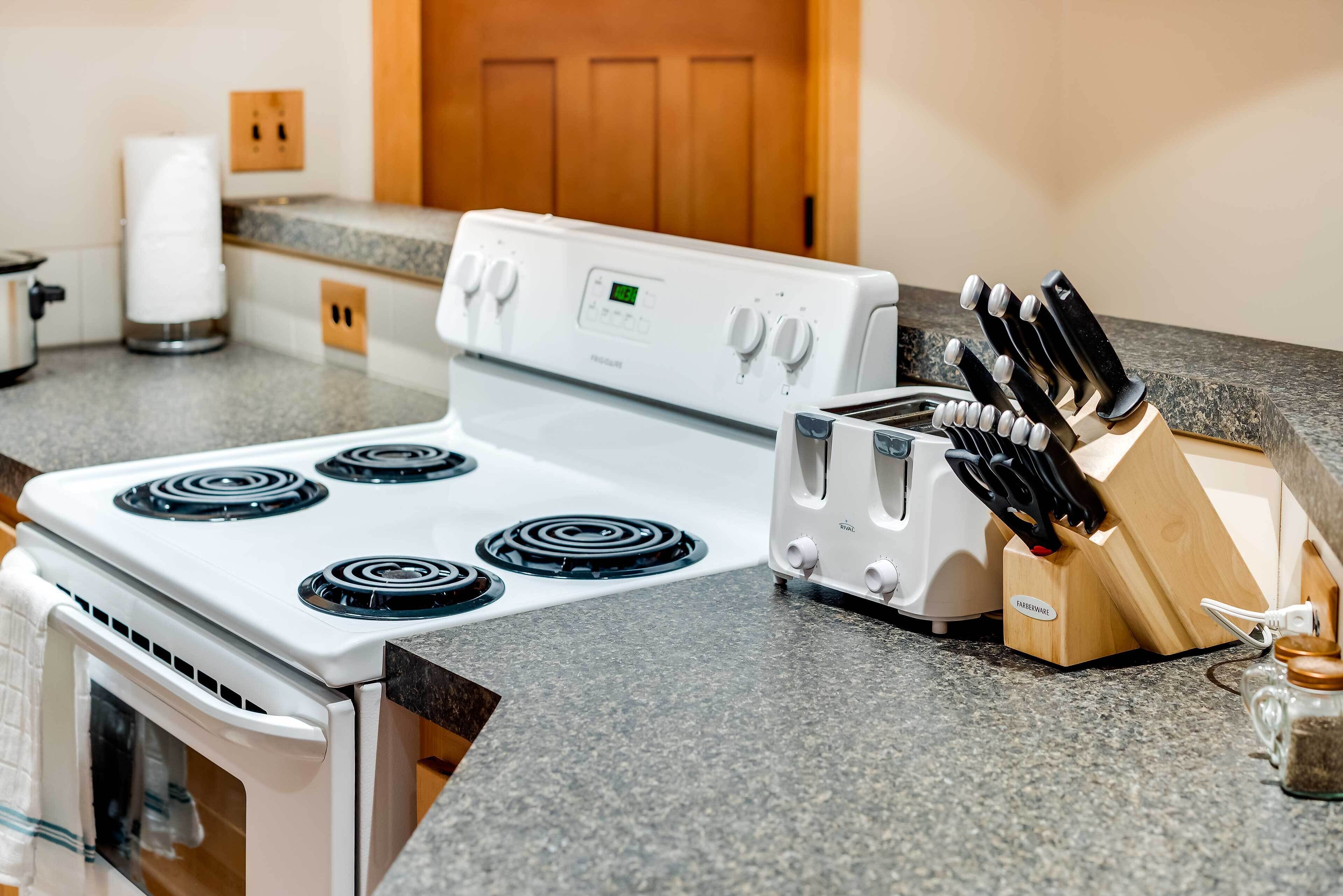 A kitchen with a white stove, a toaster, and a knife block on the countertop.