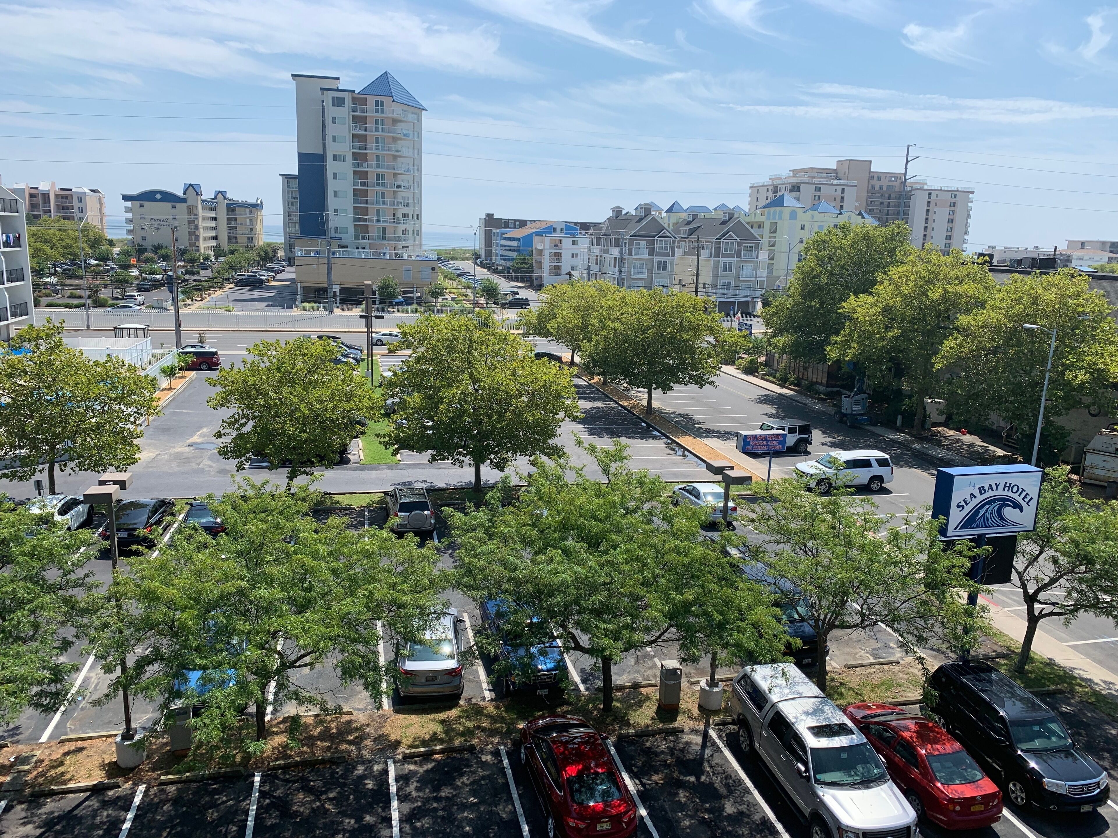 A parking lot with multiple cars and a sign for Sea Bay Hotel.