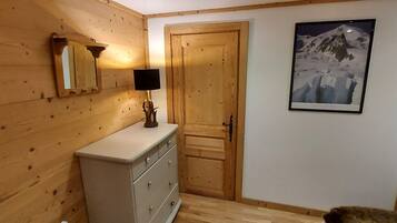 A wooden-paneled room with a dresser, a mirror, a lamp, and a framed picture on the wall.