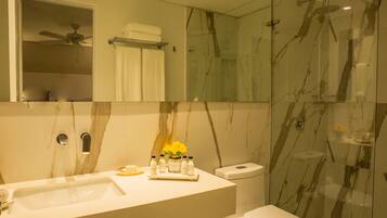 A modern bathroom with a marble vanity, a toilet, and a glass-enclosed shower.